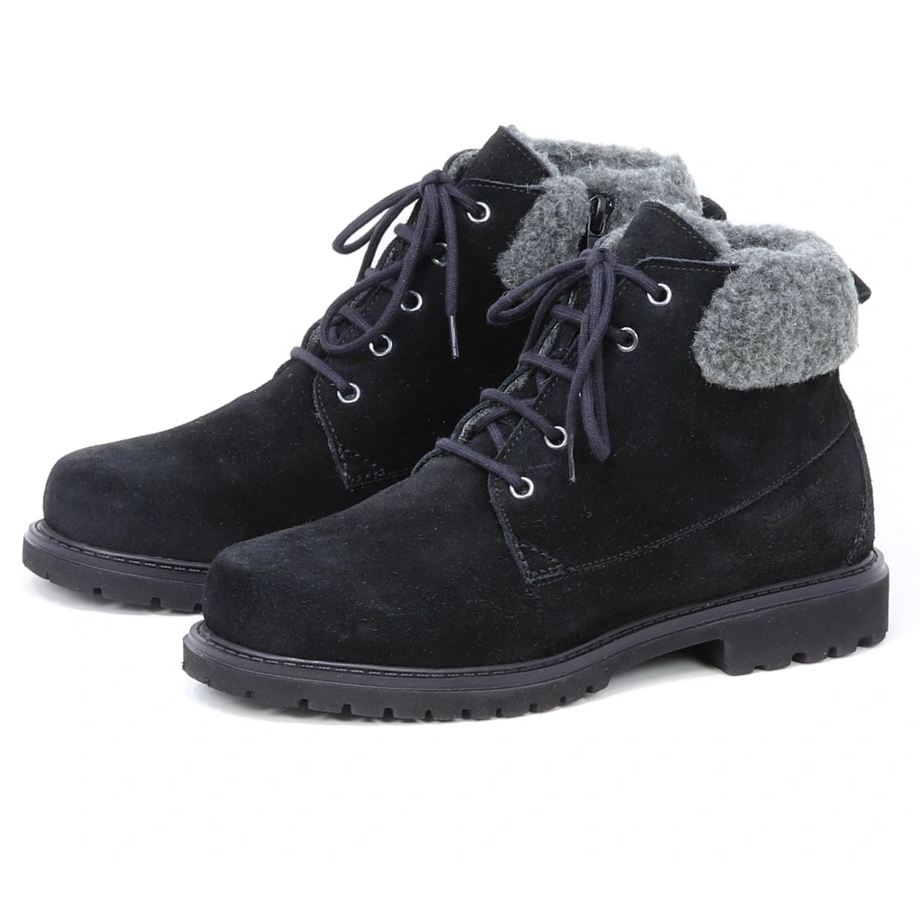 The Women’s Merano Chukka Boots—a pair of black suede lace-up ankle boots with gray fleece cuffs, rugged rubber soles, and a cozy wool shearling lining for added warmth—are positioned side by side on a white background.