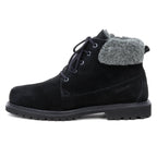 The Women’s Merano Chukka Boot is a black suede ankle boot with a gray padded collar, black laces, and a rugged rubber sole, shown in side profile on a white background. This winter chukka boot features waterproof suede and luxurious wool shearling lining for added warmth and comfort.