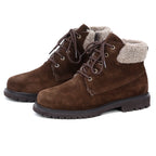 The Women’s Merano Chukka Boot is a pair of brown waterproof suede boots featuring black rubber soles and a light brown wool shearling lining around the ankle, making them a stylish choice for winter.