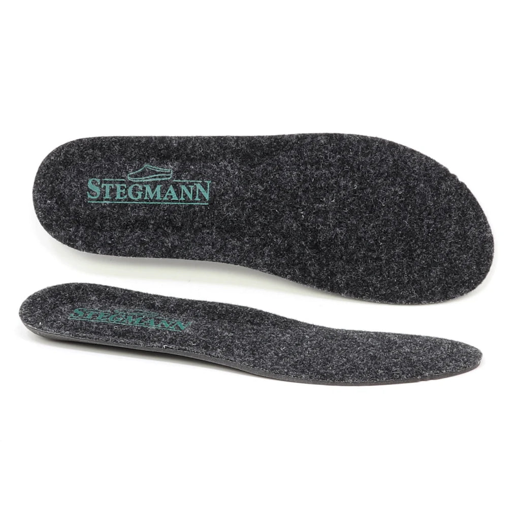 A pair of black felt Women's Wool Cushion Replacement Insoles - No Arch, featuring the word "Stegmann" and a green shoe graphic printed on the heel. These Stegmann replacement insoles deliver cushioned comfort, making them an ideal upgrade for your favorite shoes.
