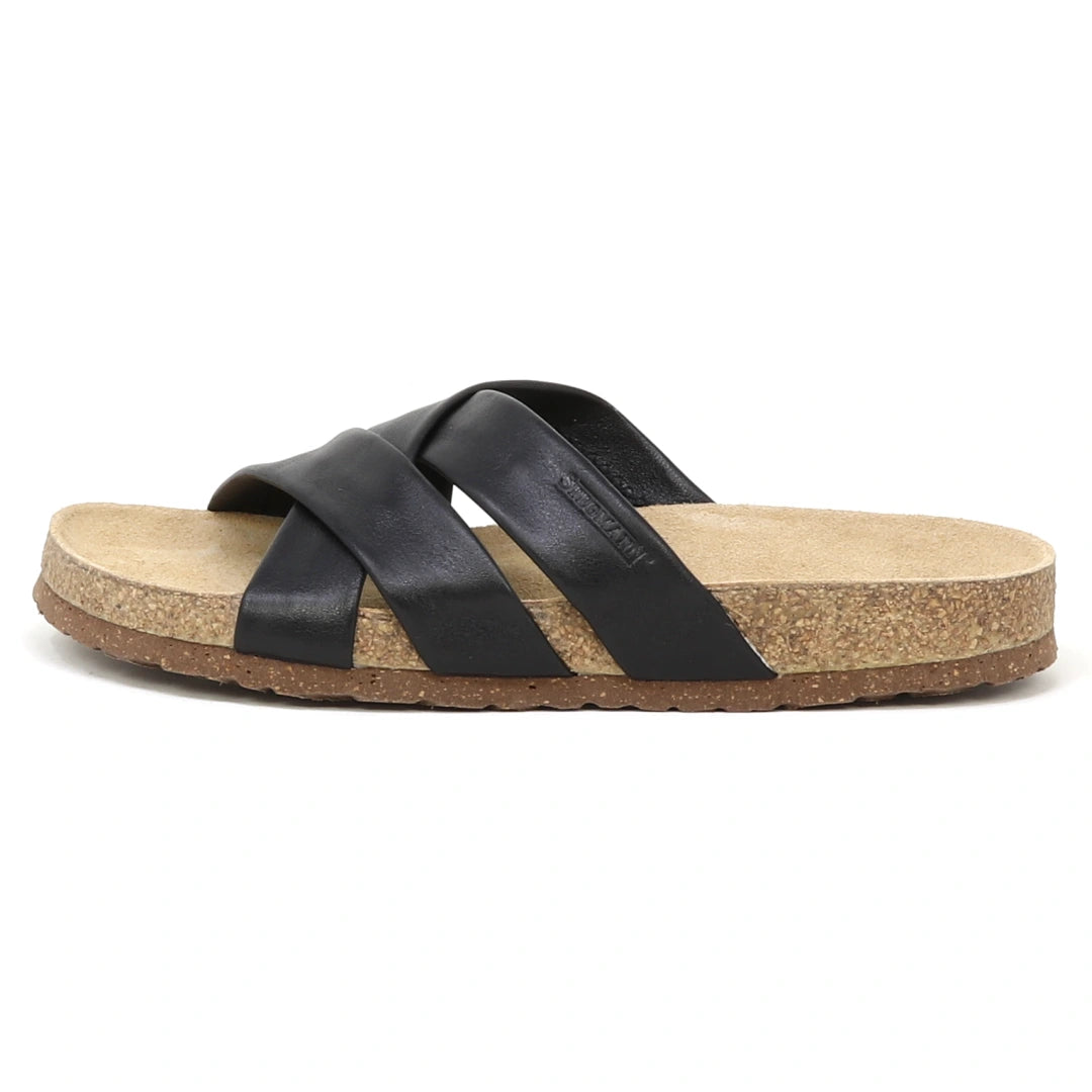 The Women's Romy Slide Sandal features black leather with two wide crisscross straps and a contoured cork footbed for comfort, shown from the side.
