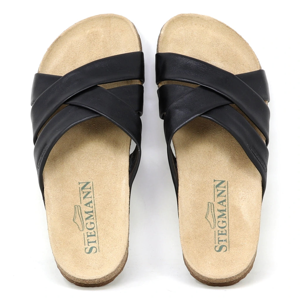 The Women's Romy Slide Sandal features black crisscross leather straps, a contoured cork footbed for comfort, and Stegmann branding on the insoles.