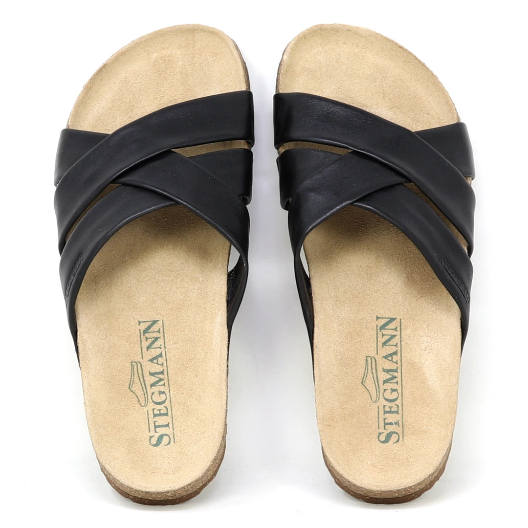 The Women's Romy Slide Sandal features black crisscross leather straps, a contoured cork footbed for comfort, and Stegmann branding on the insoles.
