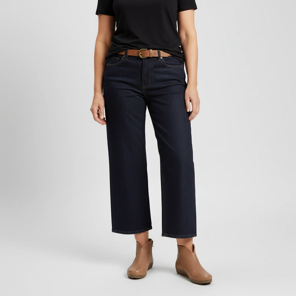 Person wearing a black t-shirt, dark blue wide-leg jeans, Women's Matching Leather Belt, and tan ankle boots stands against a plain light background.