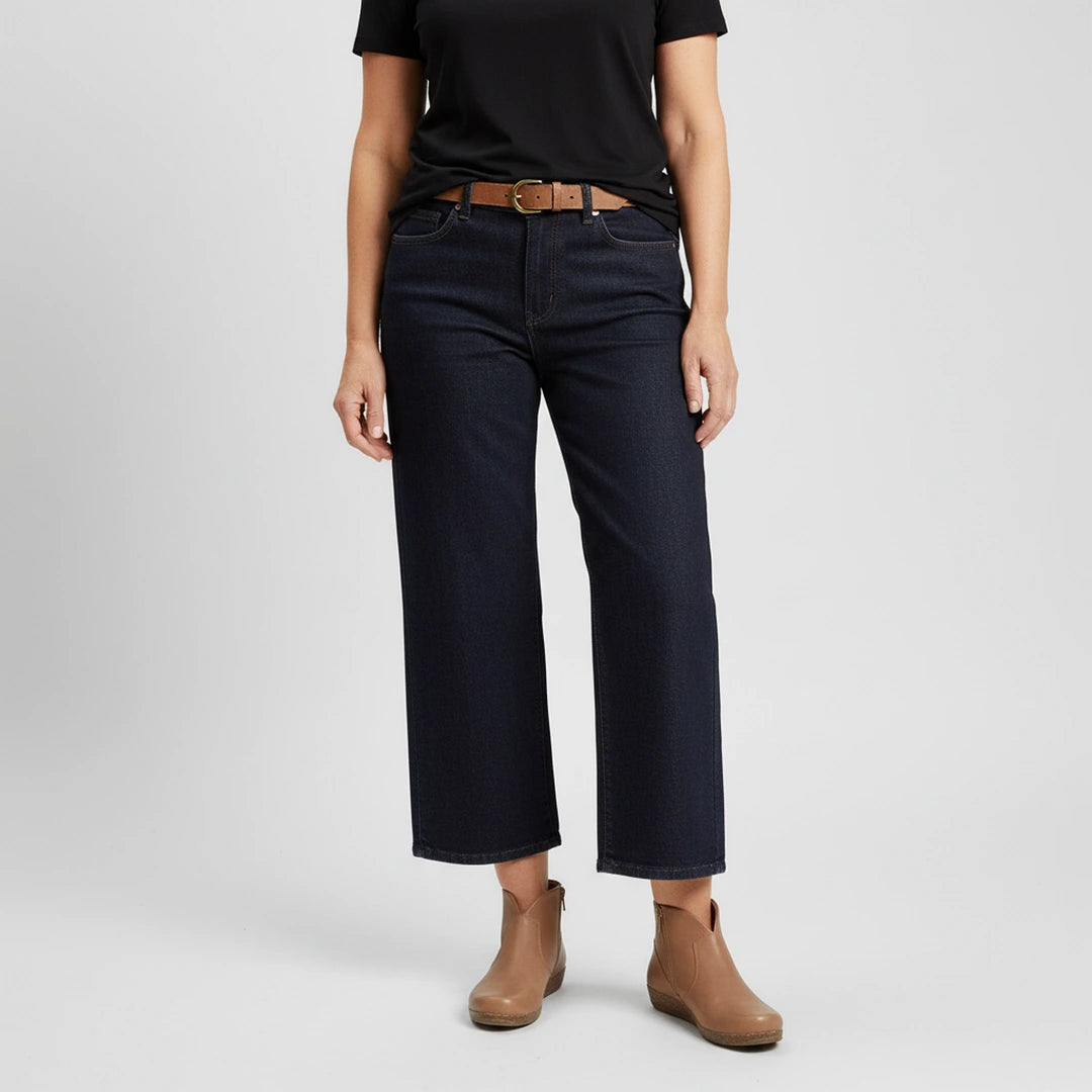 Person wearing a black t-shirt, dark blue wide-leg jeans, Women's Matching Leather Belt, and tan ankle boots stands against a plain light background.