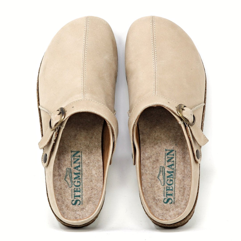 The Women's Tirol Leather Clog features beige oiled leather with side buckles, a wide toe box for comfort, and an adjustable strap for the perfect fit. The brand "Stegmann" is displayed in green on the insoles.