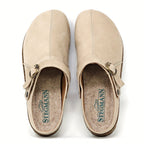 The Women's Tirol Leather Clog features beige oiled leather with side buckles, a wide toe box for comfort, and an adjustable strap for the perfect fit. The brand "Stegmann" is displayed in green on the insoles.