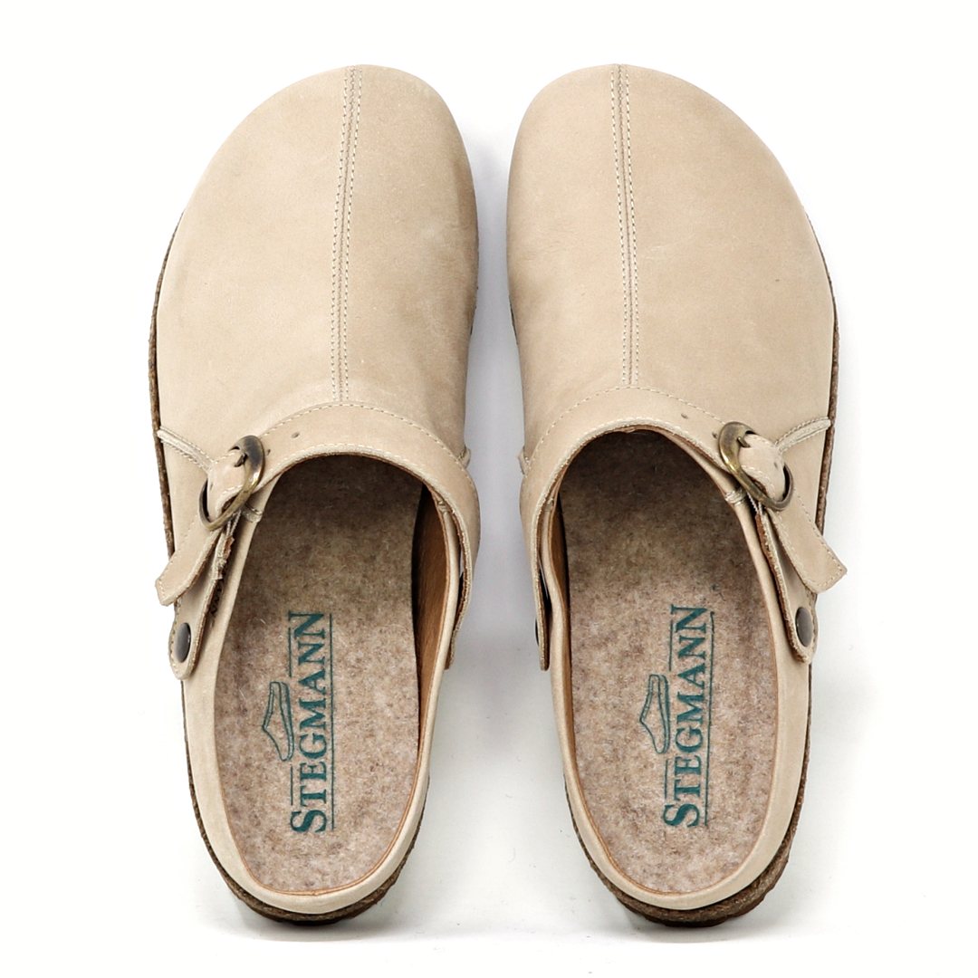 The Women's Tirol Leather Clog features beige oiled leather with side buckles, a wide toe box for comfort, and an adjustable strap for the perfect fit. The brand "Stegmann" is displayed in green on the insoles.