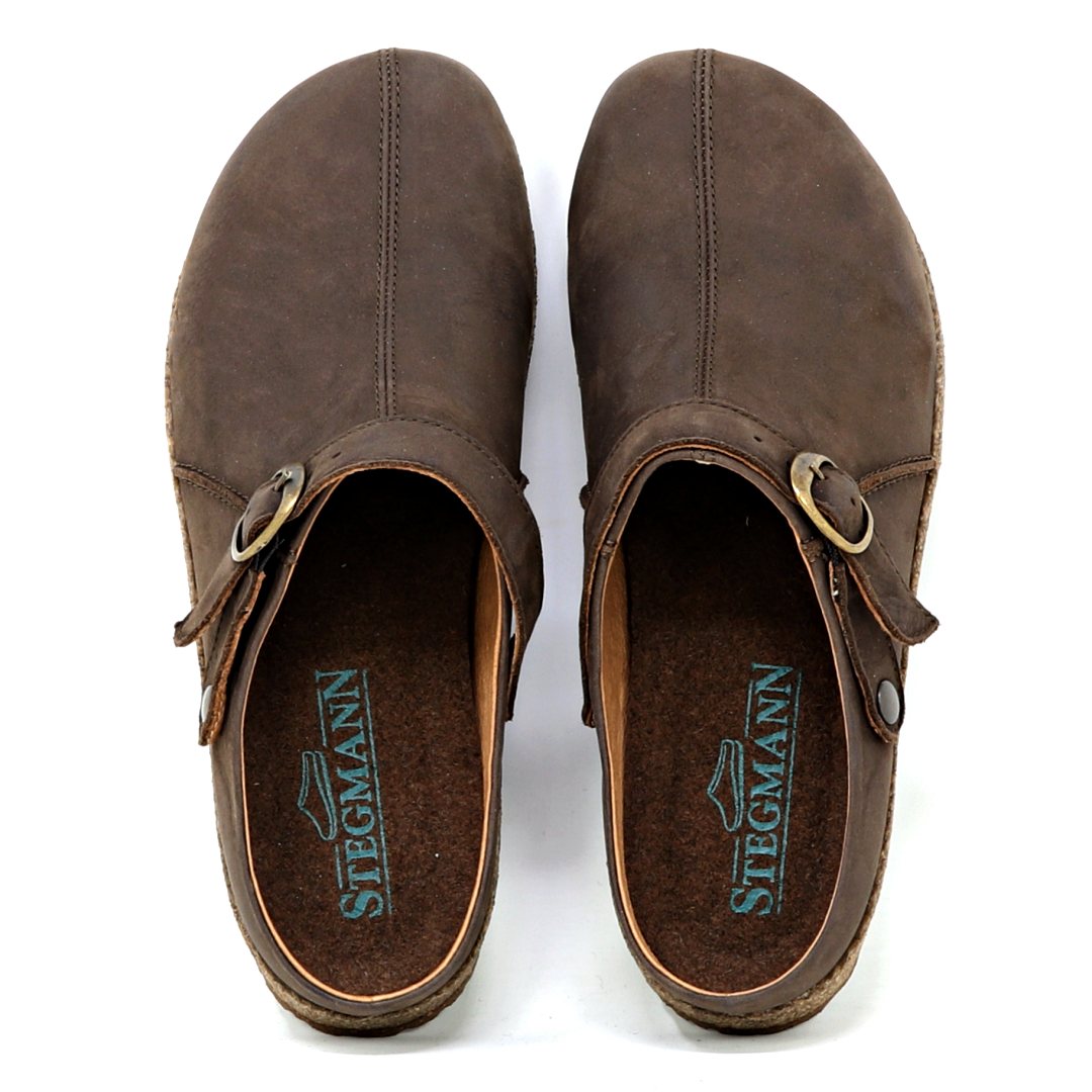The Women's Tirol Leather Clog features brown oiled leather and an adjustable buckle strap. Its view from above shows "Stegmann" on the insole and a comfortable wide toe box.