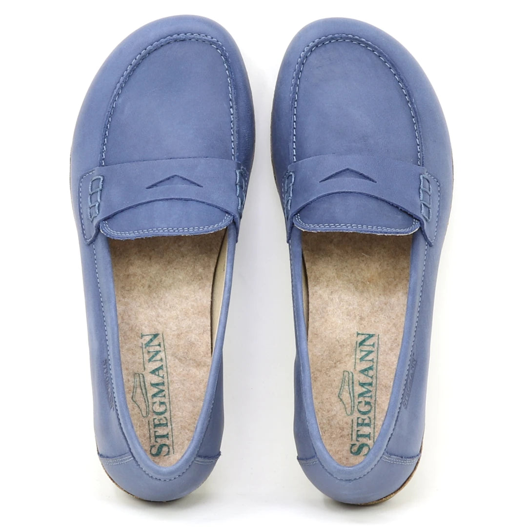 The Women's Victoria Loafer features blue nubuck, detailed stitching, and "Stegmann" branding on cushioned insoles with extra arch support, shown from a top-down view.