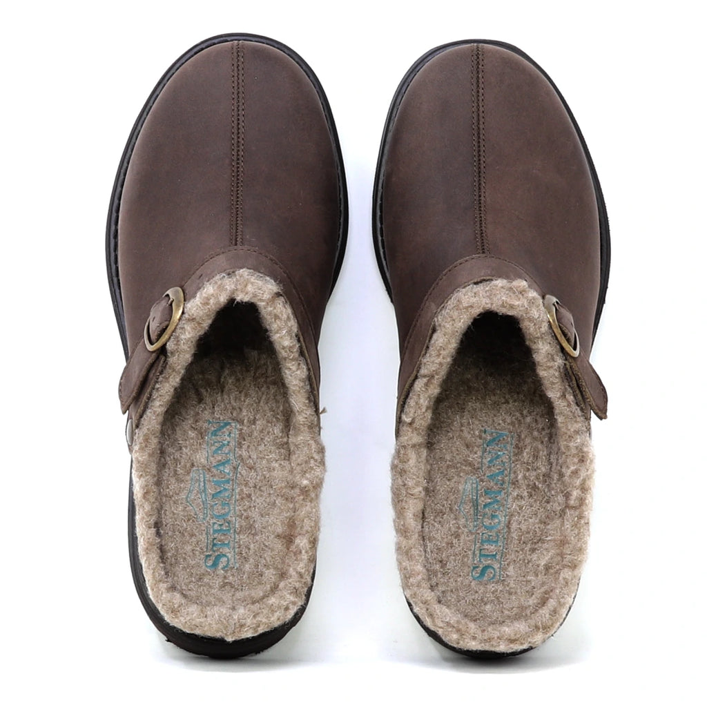 A pair of Zermatt Wool Shearling Clogs in brown, featuring buckle detail and plush beige wool shearling lining, viewed from above. The brand name “STERLING” is visible on the insoles.