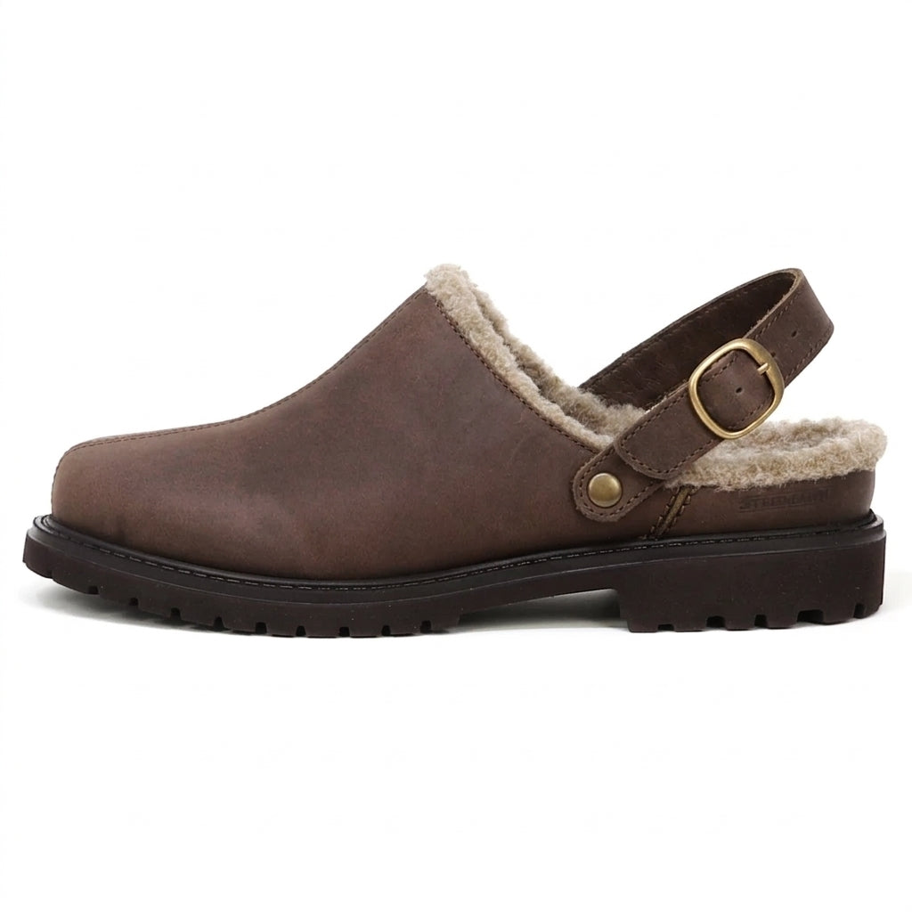 The Zermatt Wool Shearling Clog features a cozy shearling lining, brown leather slip-on design, adjustable heel strap with a gold buckle, and a rugged rubber sole, displayed on a white background.