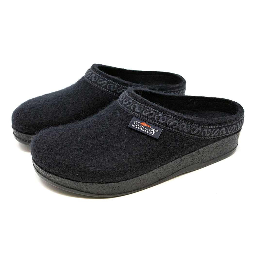 The Women's WoolFlex Wool Clog - Wide are black slip-on slippers made of Merino wool, featuring a subtle edge pattern, arch support, and a side brand label.