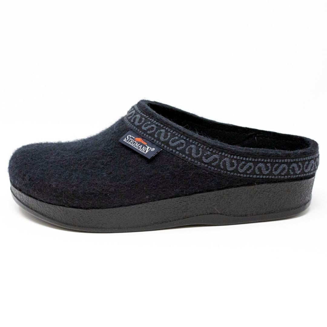 The Women's WoolFlex Wool Clog in medium size features a black Merino wool upper with decorative collar patterns, an anatomically contoured sole for cushion comfort, and a side brand label.