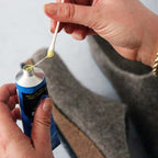 Using a cotton swab, an individual carefully applies Barge Shoe Repair Cement to a wool shoe, ensuring a precise and efficient repair.