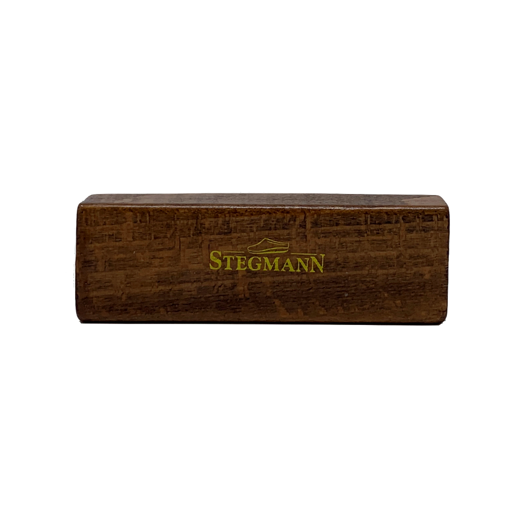 Rectangular wooden block engraved with "STEGMANN" in green, evoking the high-quality craftsmanship of Stegmann clogs; part of the Wool & Cork Care Kit - Brush & Sealer.