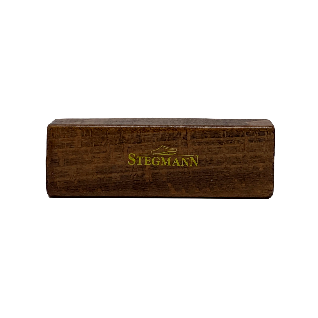 Rectangular wooden block engraved with "STEGMANN" in green, evoking the high-quality craftsmanship of Stegmann clogs; part of the Wool & Cork Care Kit - Brush & Sealer.