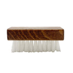 Side view of a brush with white bristles, part of the Wool & Cork Care Kit - Brush & Sealer, features a wooden handle that echoes the natural textures seen in Stegmann clogs against a white background.