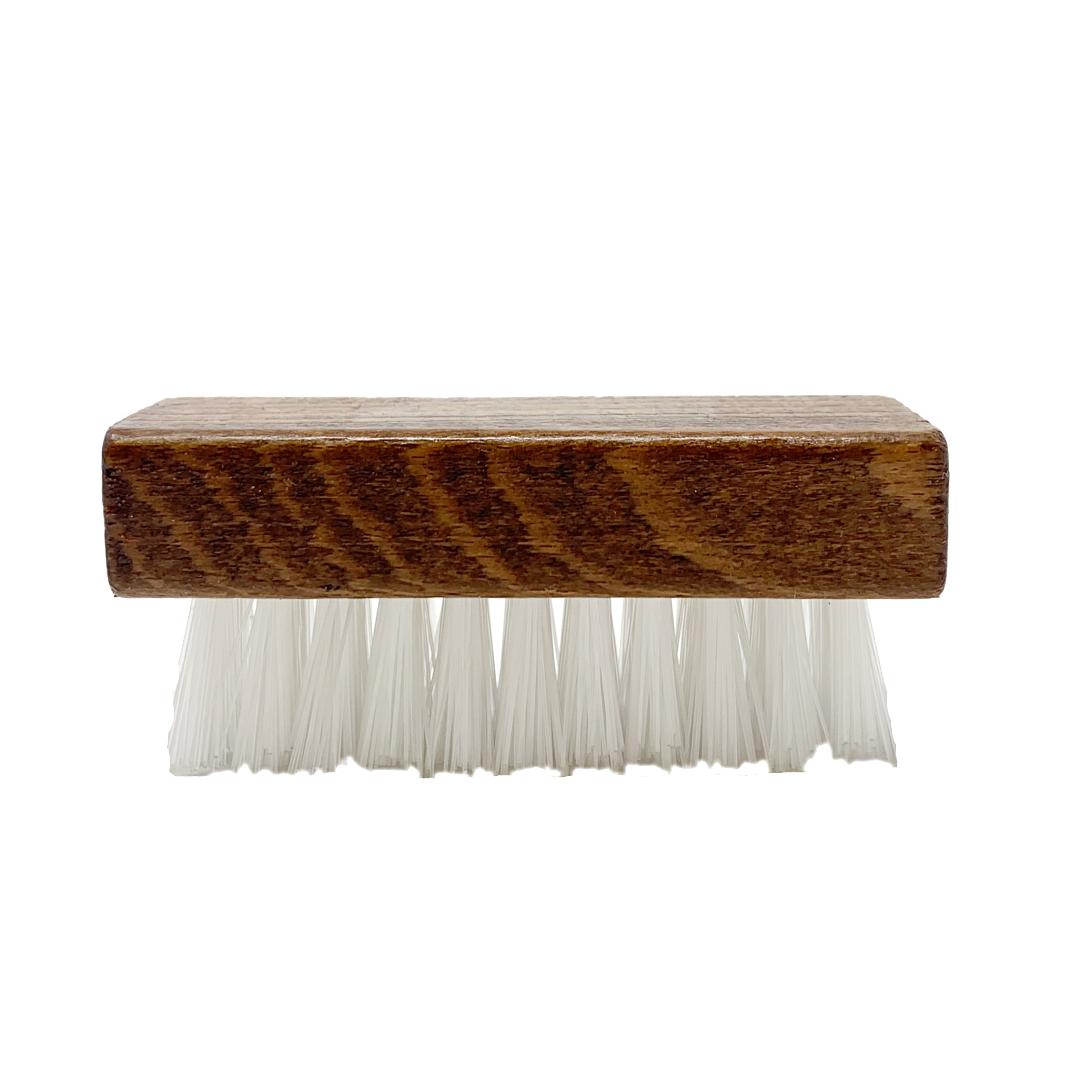 Side view of a brush with white bristles, part of the Wool & Cork Care Kit - Brush & Sealer, features a wooden handle that echoes the natural textures seen in Stegmann clogs against a white background.