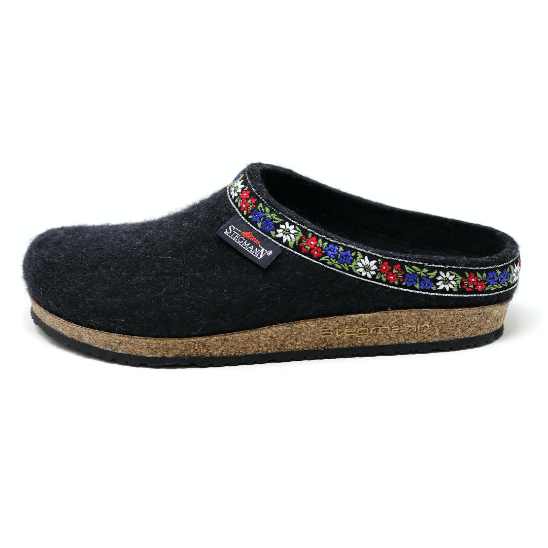 The Women's Edelweiss Wool Clog - Medium is a black slip-on with a cork sole, featuring an embroidered floral trim inspired by classic Edelweiss clogs.