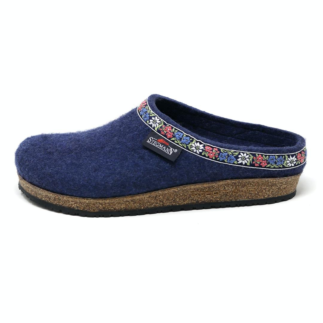 The Women's Edelweiss Wool Clog - Medium features blue Merino wool with a cork sole, an embroidered floral band inspired by Edelweiss clogs, and a small side tag.