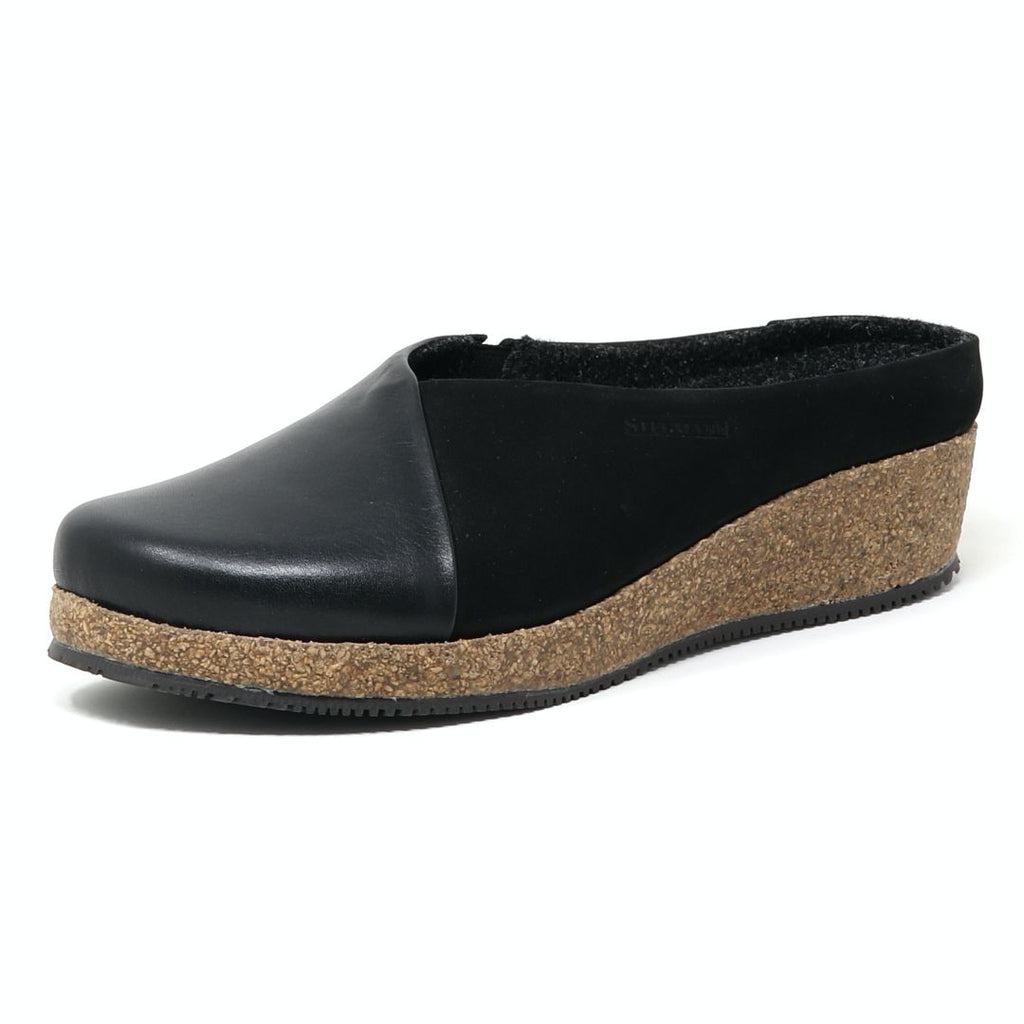 The Women's Elsa Leather & Nubuck Wedge Mule is a black slip-on clog with a wedge cork sole and slightly raised back heel, crafted in leather and nubuck. It includes a removable wool-lined arch support insole for all-day comfort.