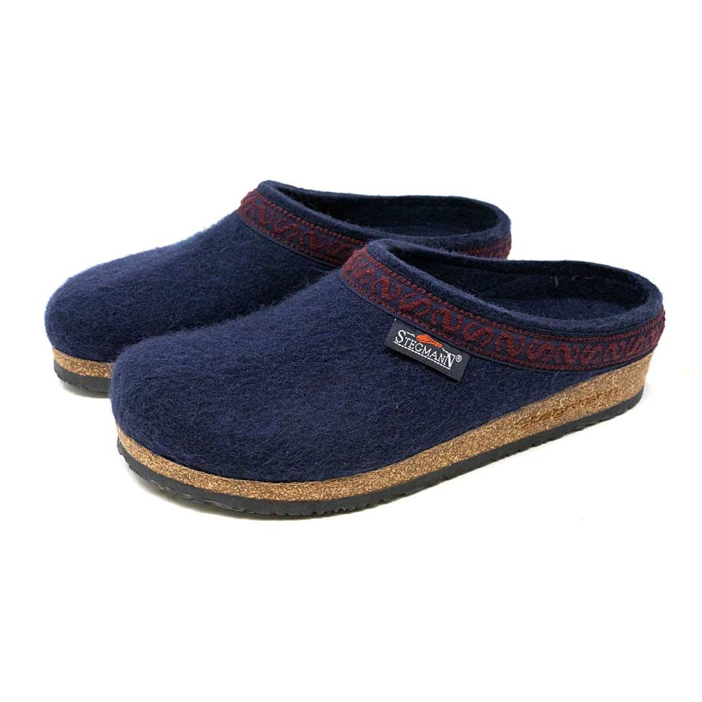 The Women's Original 108 Wool Clog - Medium is a pair of dark blue slippers for women, crafted from Merino wool felt and featuring a stylish brown trim along with comfortable cork and latex soles.