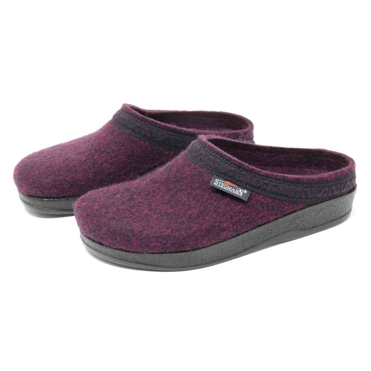 The Women's WoolFlex Wool Clog - Wide is a pair of purple Merino wool felt clogs, adorned with black trim and soles, and includes a brand tag on one shoe. These stylish clogs offer excellent arch support and all-day comfort.