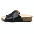 The Women's Layna Leather Wedge Sandal, crafted in black leather with a sustainable cork midsole and closed toe design, features a cushioned suede footbed for extra comfort, shown on a plain background.