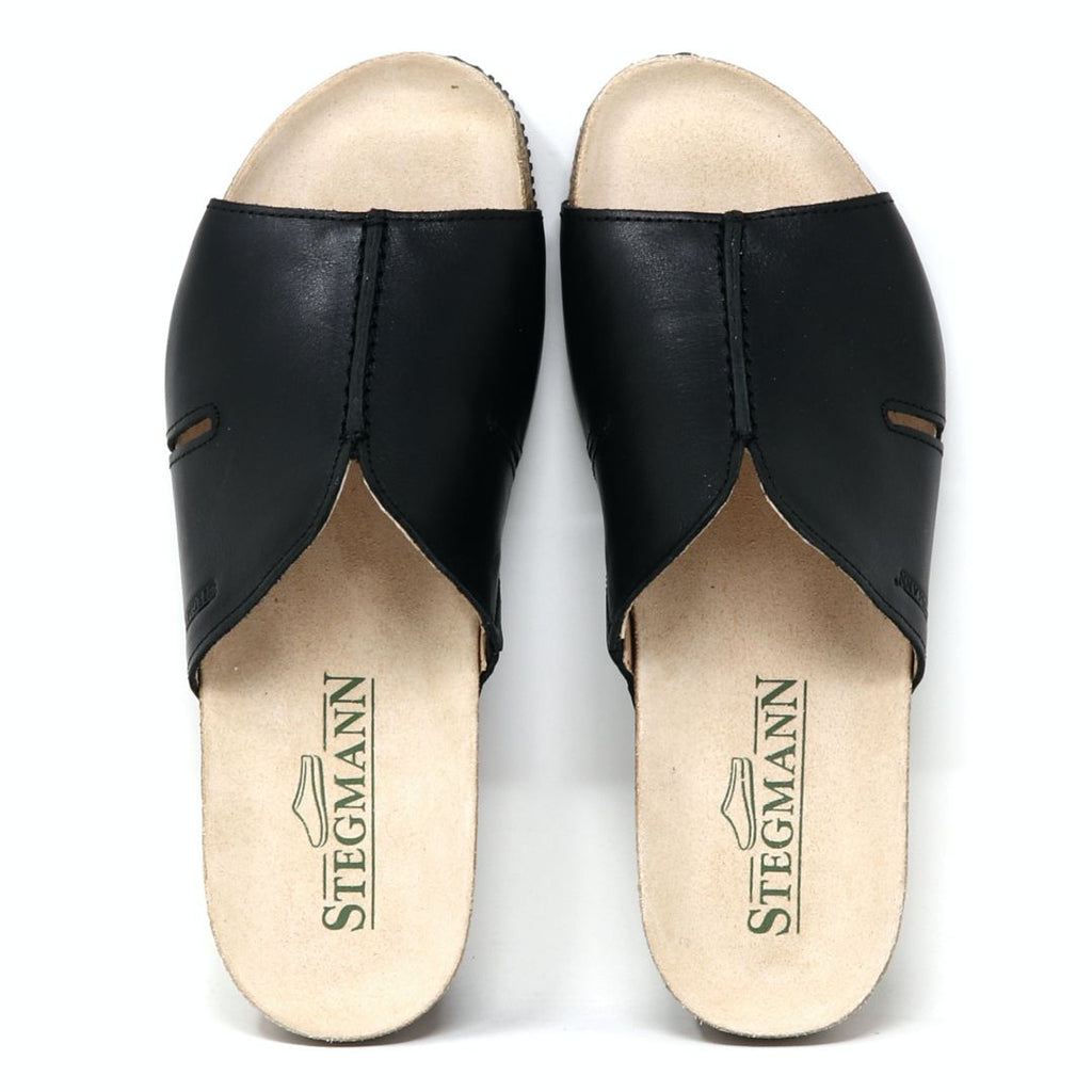Women's Layna Leather Wedge Sandal in black features open-toe design, cushioned suede footbed, and beige insoles with "Stegmann" printed in green. The sustainable cork midsole completes the look from above.