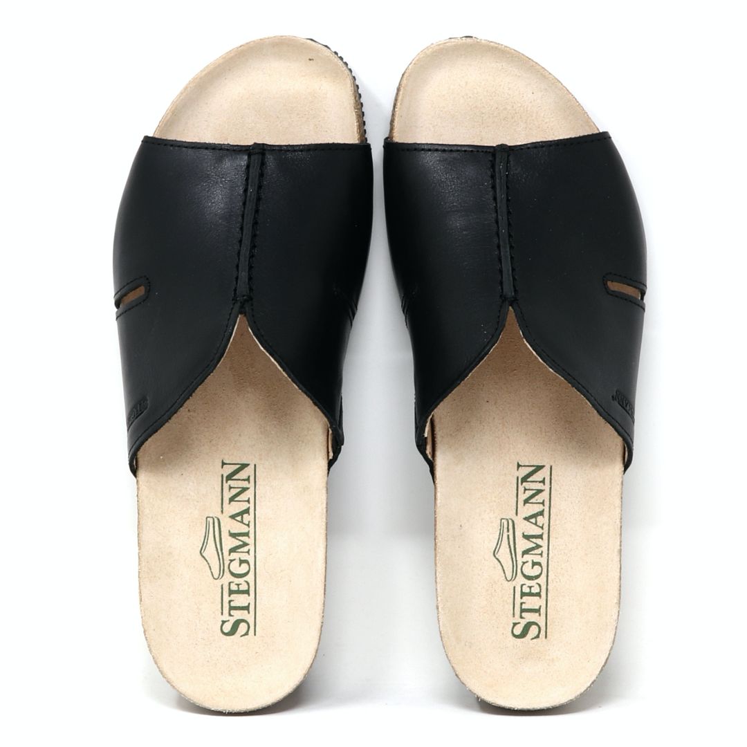 Women's Layna Leather Wedge Sandal in black features open-toe design, cushioned suede footbed, and beige insoles with "Stegmann" printed in green. The sustainable cork midsole completes the look from above.