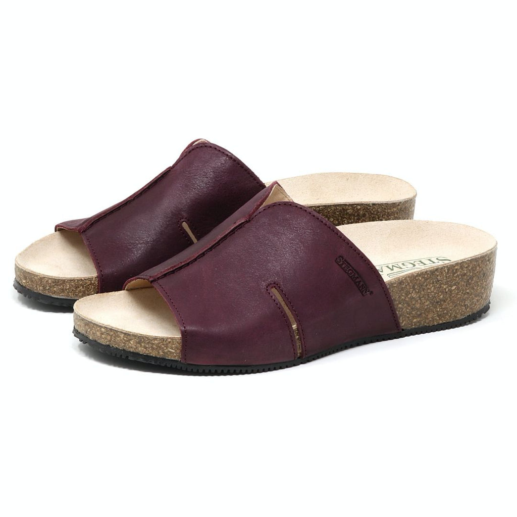 The Women's Layna Leather Wedge Sandal combines a cushioned suede footbed with eco-friendly cork midsoles, offering a brown open-toe slip-on design and sturdy black rubber outsoles.