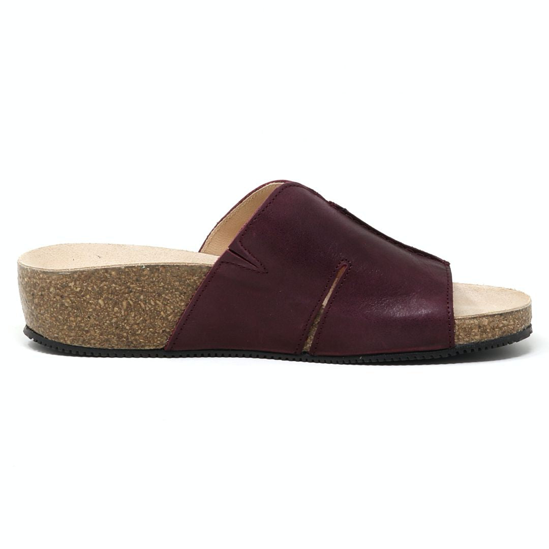 The Women's Layna Leather Wedge Sandal is a maroon slide with an open toe, sustainable cork wedge sole, and cushioned suede footbed for comfort, elegantly framed against a white background.