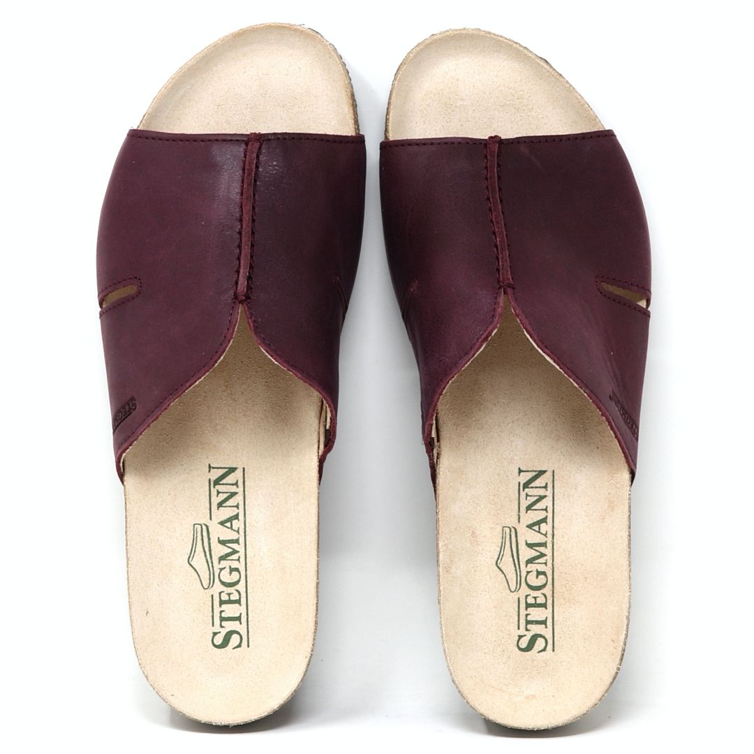 A pair of Women's Layna Leather Wedge Sandals with a stylish brown leather slip-on design, cream insoles, cushioned suede footbed, and sustainable cork midsole, viewed from above.