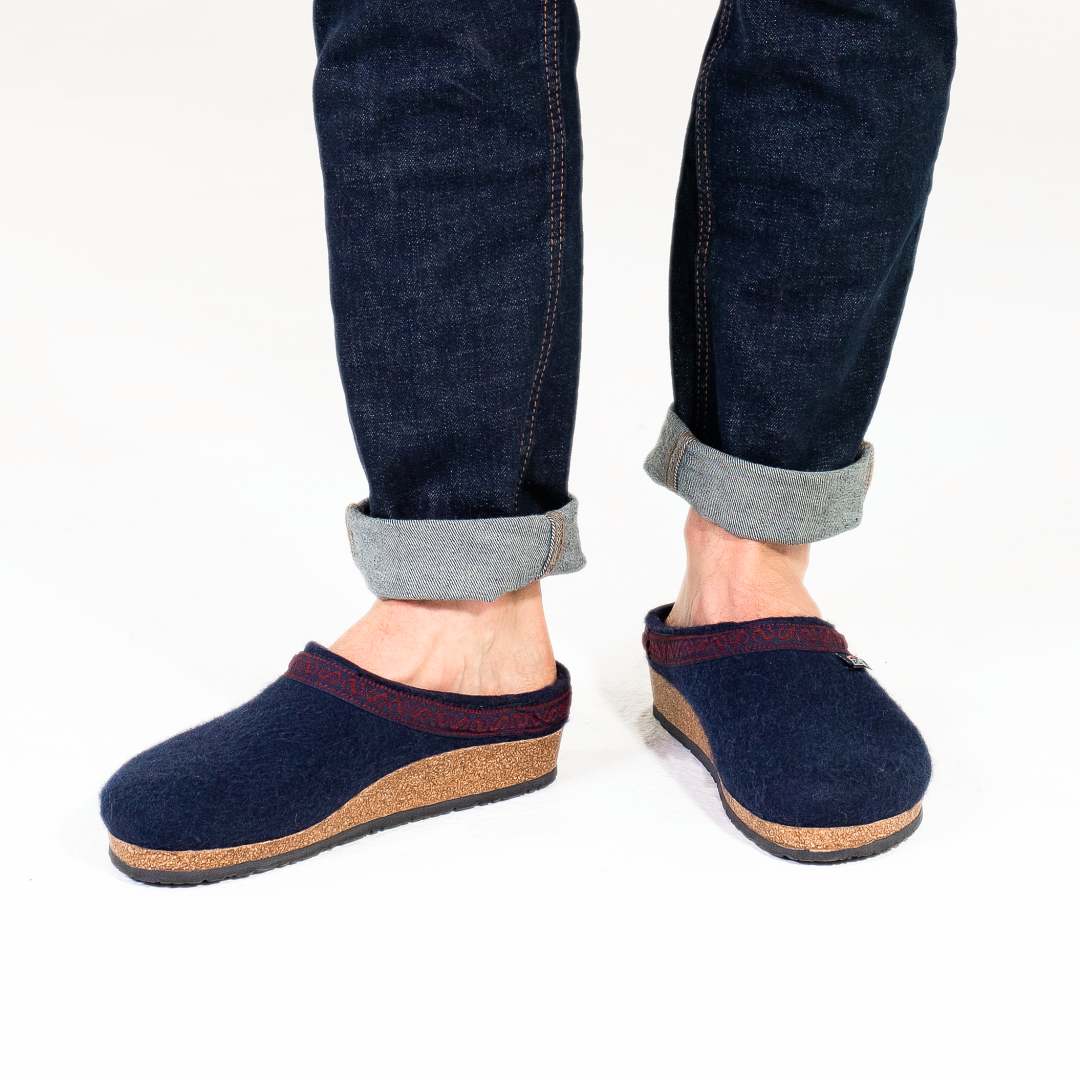 A person wearing rolled-up jeans and the Men's Original 108 Wool Clog, featuring a cozy Merino wool upper and cork support sole, on a white background.