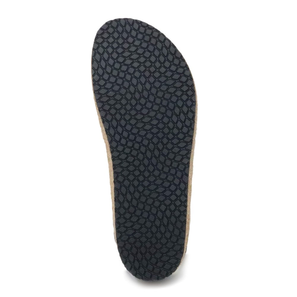 The image displays the sole of the Women's Essenz Wool Clog, featuring a textured design with interlocking scales in a dark hue, paired with a comfortable cork/latex footbed.